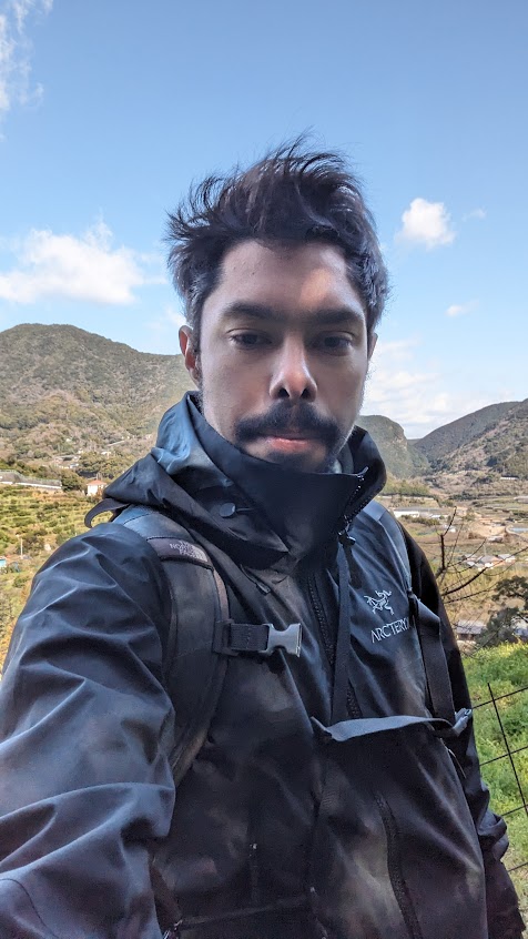 Tyler in a mountainous area with a backpack, clear sky background.