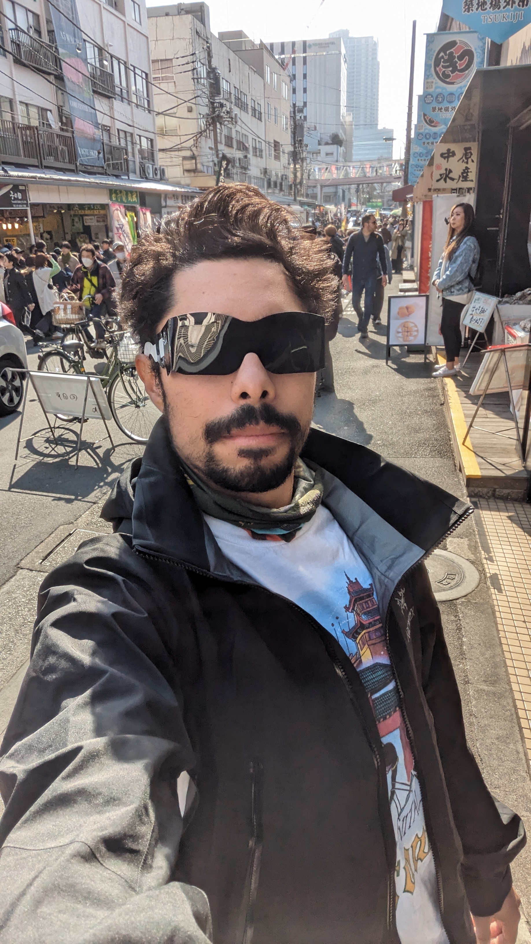Tyler on a busy urban street, wearing a black jacket and sunglasses.