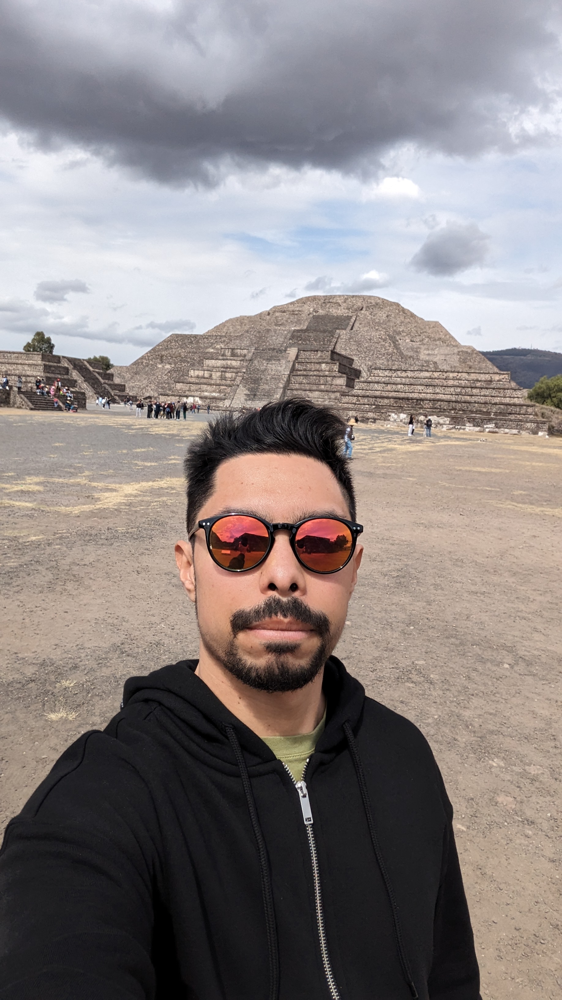 Tyler in front of a stone pyramid, wearing a black hoodie and red sunglasses.